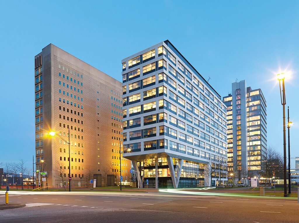 Modern office buildings at De Entree in Amsterdam illuminated during dusk.